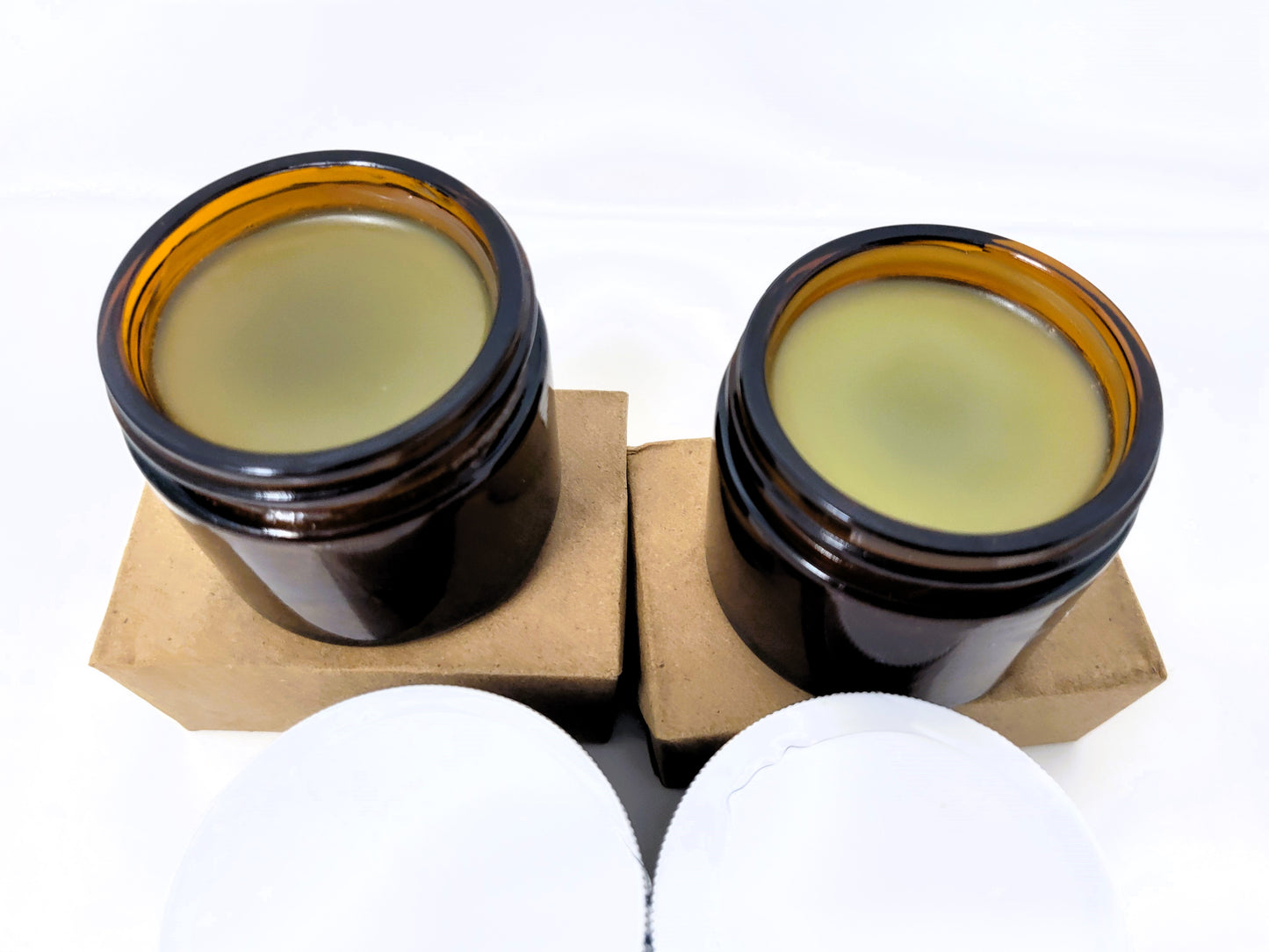 Two open amber jars of Sisters of the Valley CBD Topical Salve 8 oz. (Lavender or Mint, ~1,000 mg CBD) rest atop cardboard boxes. White lids are visible below, all against a plain white background.